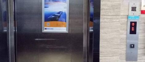 An elevator with a digital display and a poster on the door.
