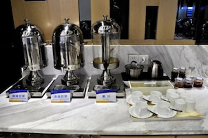 En hotelmorgenmad med tre kaffemaskiner, udvalg af drikkevarer og et varieret udvalg af retter.