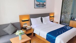 A hotel room with a bed, bedside tables, a sofa, a small table with a vase, and a painting on the wall. - Yeste Hotel (Yulin Culture Square) (Yulin)