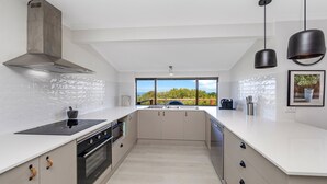 A modern kitchen with a large window, white cabinetry, and a built-in oven.