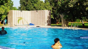 A swimming pool with clear blue water, surrounded by a tiled wall and trees. - Camp Dilly (Borsad)