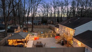 Un patio trasero con porche techado, mobiliario exterior e iluminación con guirnaldas.