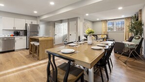 Una cocina moderna con comedor, que incluye una mesa de madera para cuatro personas, horno empotrado y refrigerador.