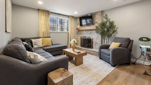 Una sala de estar con sofá, sillón y chimenea.