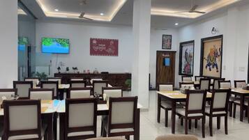 Un comedor amplio con varias mesas y sillas, ventiladores de techo y obras de arte colgadas en la pared.