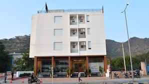 Ein mehrgeschossiges Gebäude mit modernem Design, das eine auffällige Eingangspforte mit Glastüren und einer verzierten Fassade zeigt.