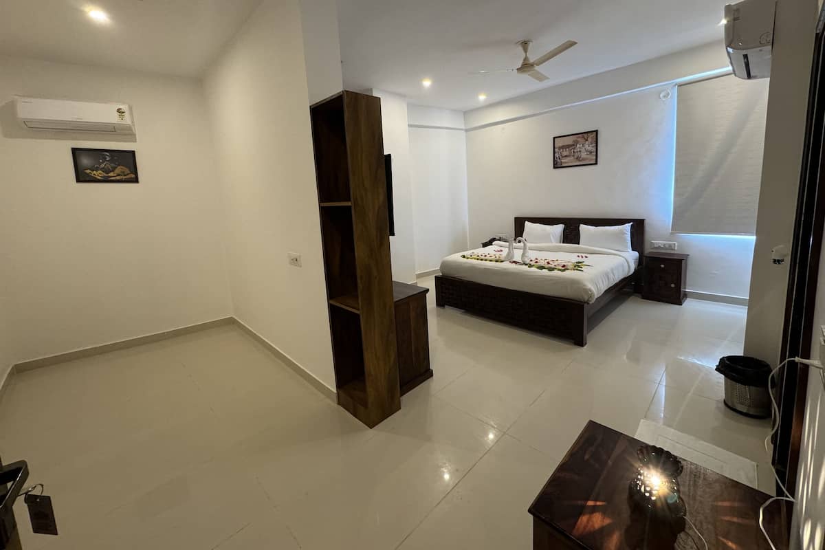 Quarto de hotel moderno com uma cama grande, um guarda-roupa de madeira, um ventilador de teto, um ar condicionado e uma pequena mesa de cabeceira.
