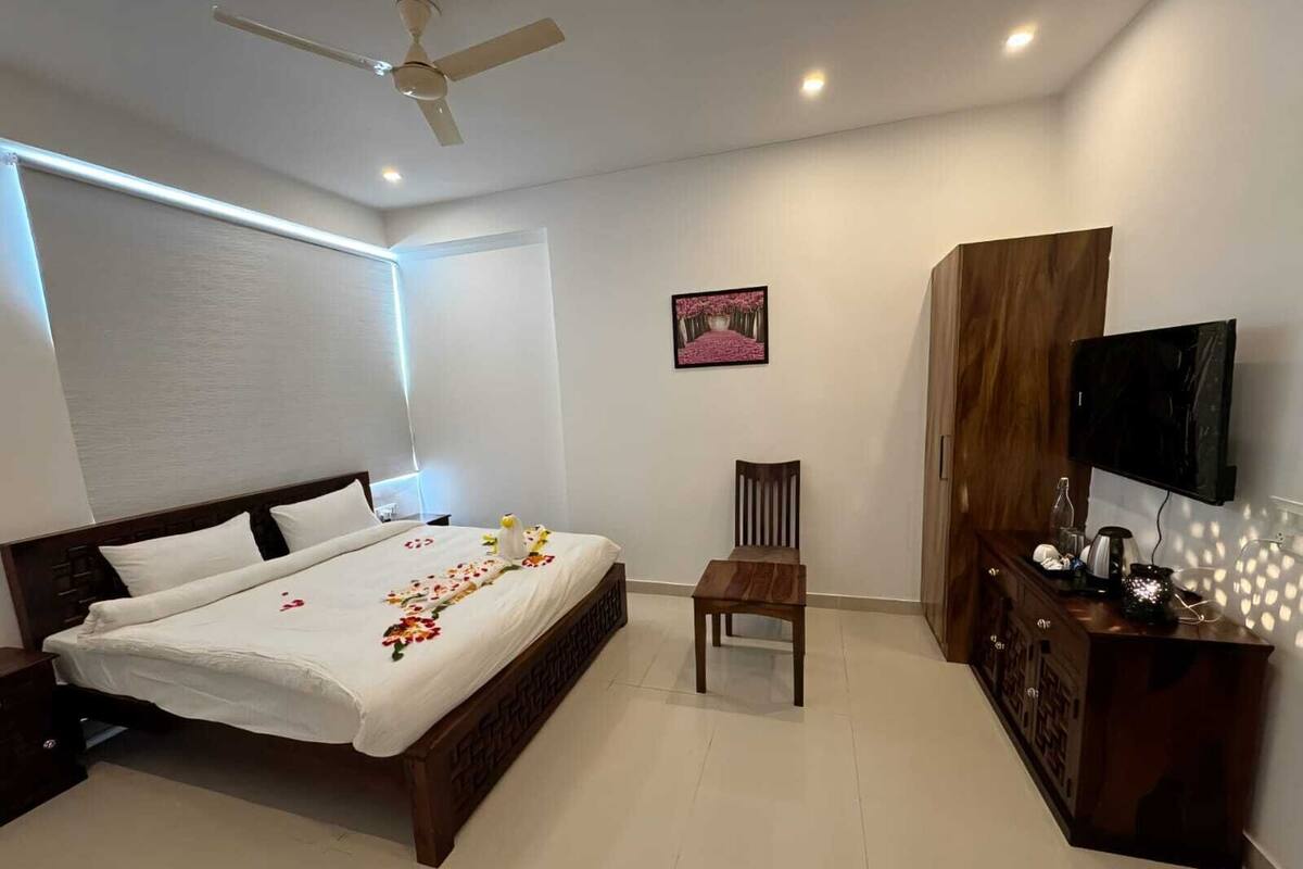 Quarto de hotel com uma cama, uma cadeira, uma televisão e um armário de madeira.