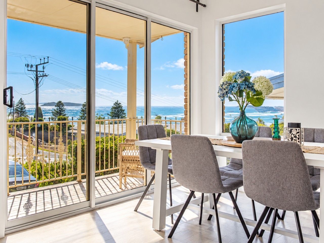 Un'area pranzo con tavolo e sedie, vista sul mare e un balcone con ringhiera.