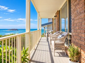 A balcony with wicker furniture, a tiled floor, and a view of the ocean.