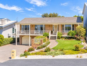 A two-story house with a garage, a covered porch, and a landscaped front yard.