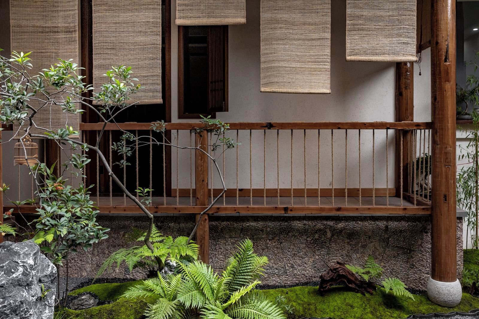 A traditional Japanese-style building with tatami mat-covered floors, a wooden balcony, and a moss-covered garden.