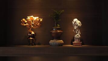 A dark room with three shelves, each holding a plant and a rock sculpture.