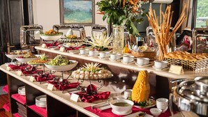 A buffet setup with various food items and beverages, including salads, fruits, and bread, arranged on a marble counter with red napkins and silverware. - AE CRUISE HALONG BAY (Tuan Chau)