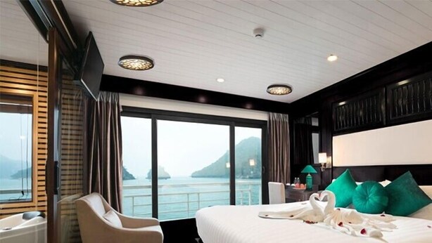 A hotel room with a large bed, a sitting area, and a view of the sea. - AE CRUISE HALONG BAY (Tuan Chau)