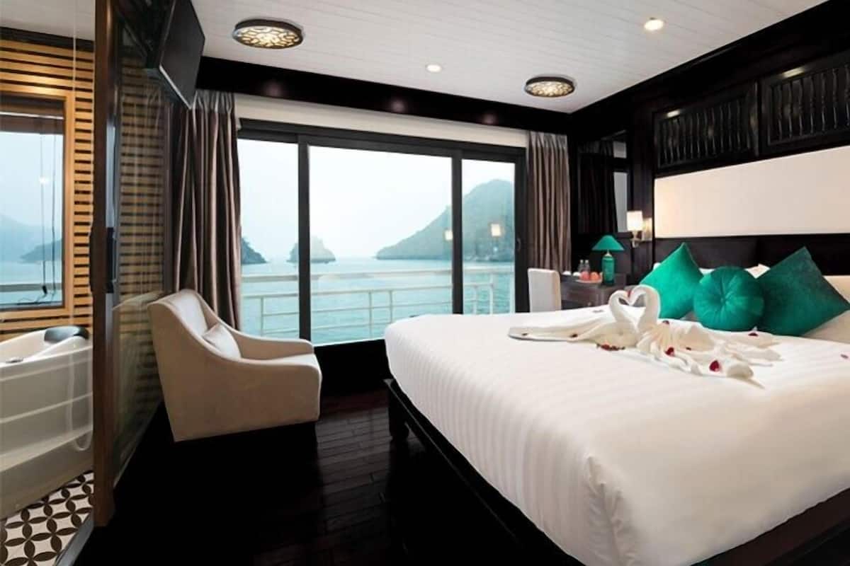 A hotel room with a large bed, a sitting area, and a view of the sea.