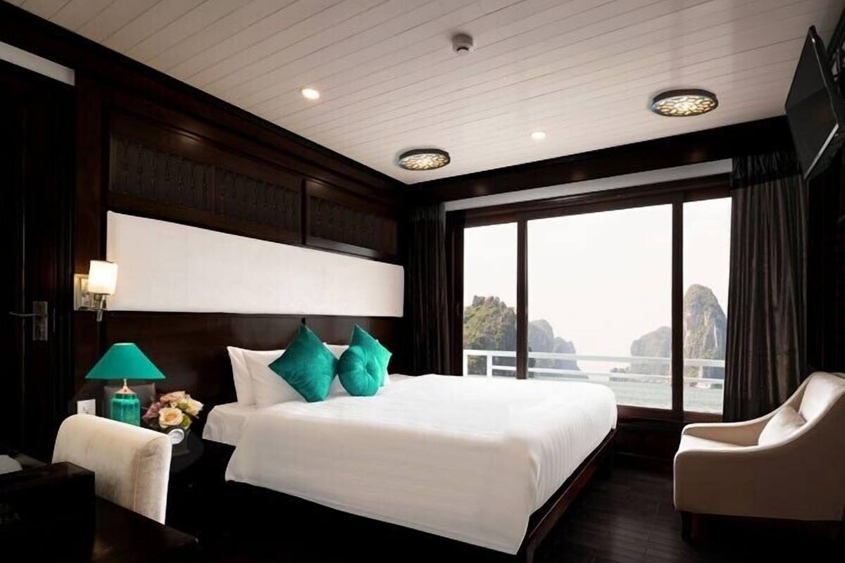 A hotel room with a large bed, a nightstand, a chair, and a view of the water.