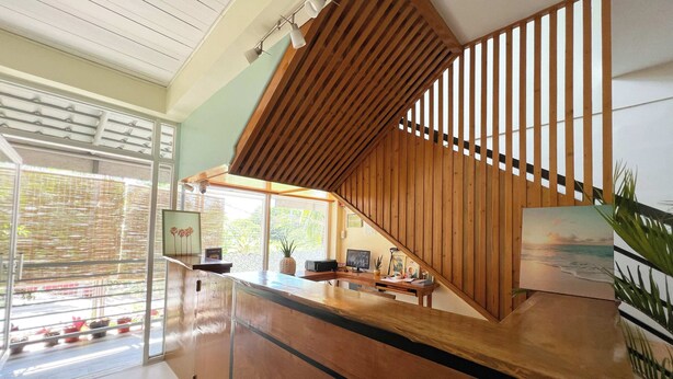 Un comptoir d’accueil avec un revêtement en bois, un escalier avec des rampes en bois et une vue sur l’extérieur grâce à de grandes fenêtres.