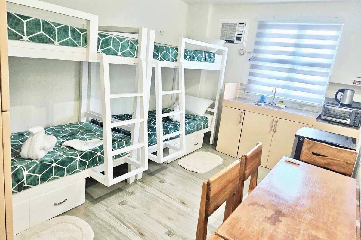 Habitación pequeña con literas, kitchenette y zona de comedor.