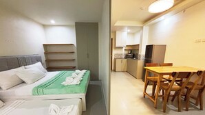 Une chambre d’hôtel avec deux lits, une petite kitchenette et un coin repas comprenant une table et des chaises.
