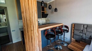 A modern kitchen with a wooden island, bar stools, and pendant lighting.