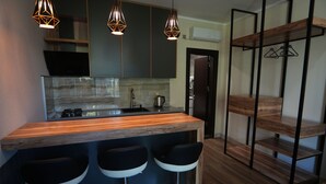 A modern kitchen with a wooden countertop, black bar stools, and pendant lighting.