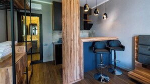 A modern interior with a wooden accent wall, a kitchen area, and two bar stools.