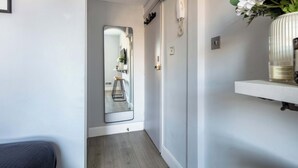 A hallway with a mirror reflecting a room, a telephone, and a shelf with a vase. - Cosy 1BR Steps from Camden Market & Regent's Park (London)