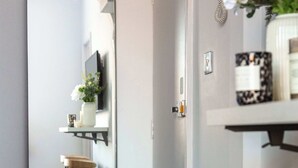 A modern bathroom with a large mirror, a wooden stool, and a shelf with toiletries. - Cosy 1BR Steps from Camden Market & Regent's Park (London)