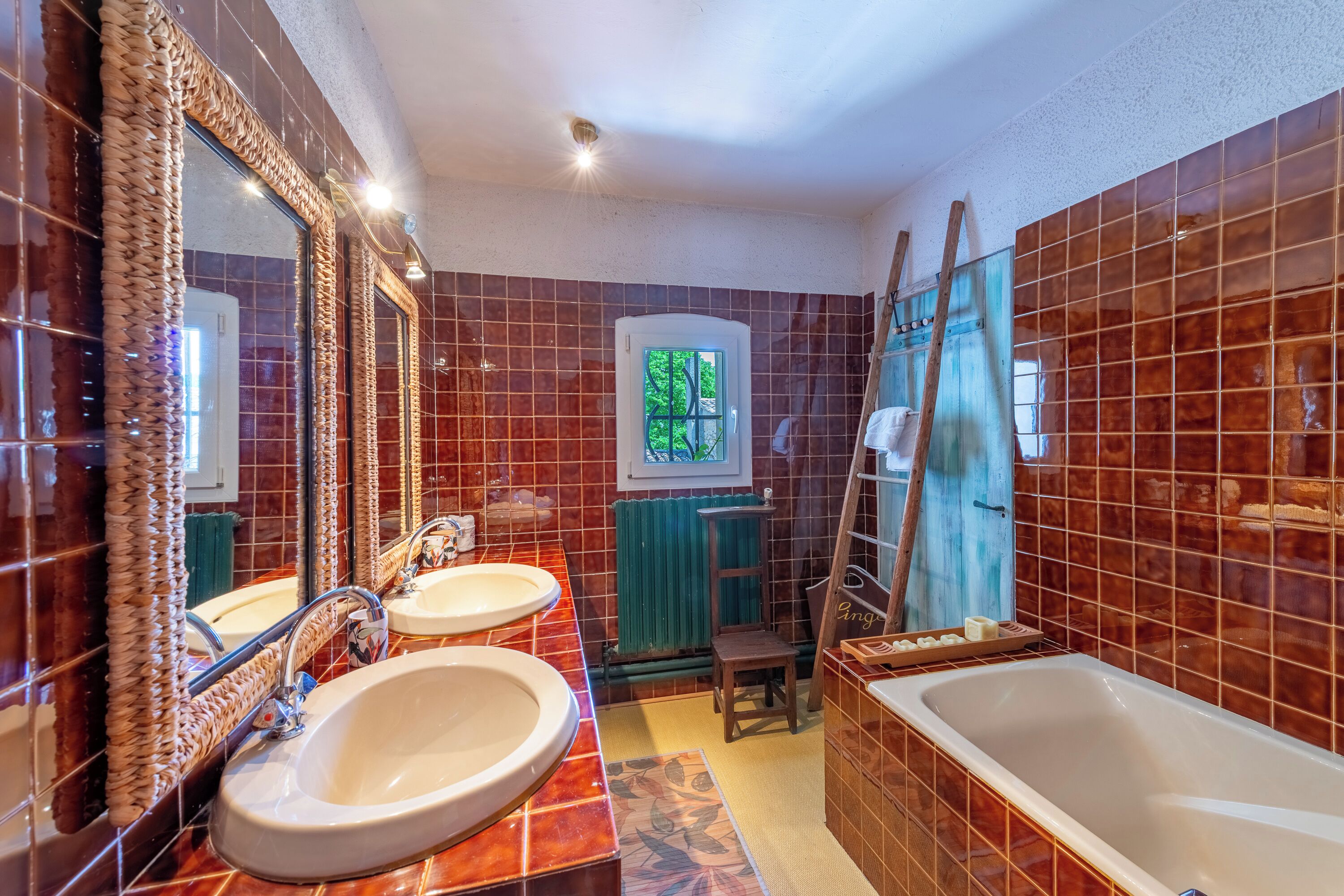 A bathroom with two sinks, a bathtub, and a mirror with a decorative frame.