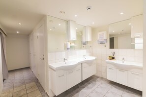 A modern bathroom with two sinks, a mirror, and a shower area. - Hostel Fjordur (Hafnarfjörður)