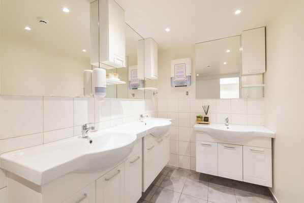 Une salle de bain moderne avec deux lavabos, un miroir et un sèche-mains.