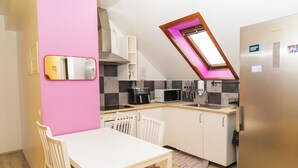 A compact kitchen with a white table and chairs, a microwave, a toaster, and a sink. - Hostel Fjordur (Hafnarfjörður)