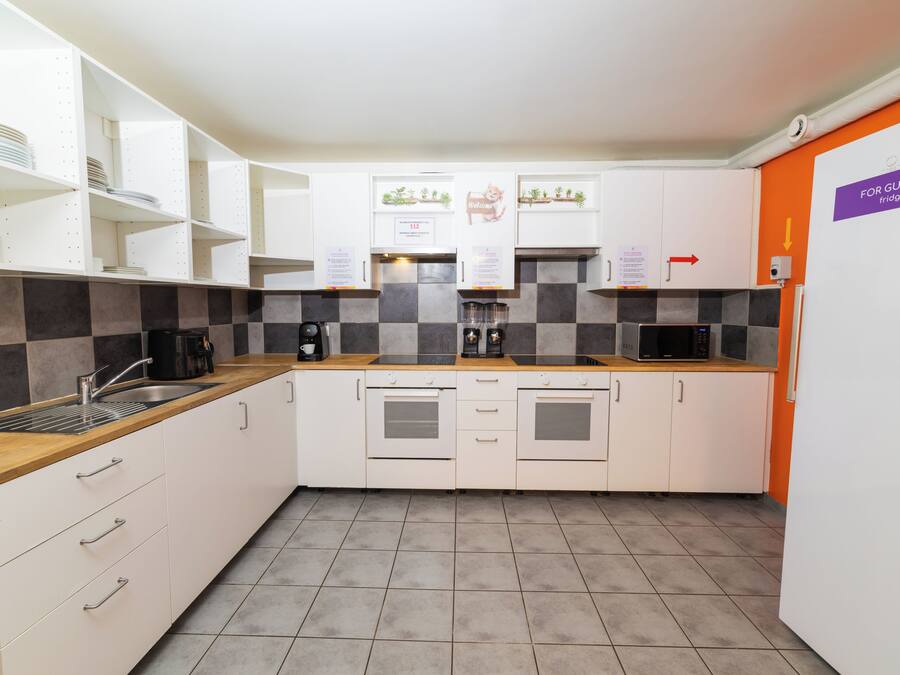 A modern kitchen with white cabinets, a checkered backsplash, and a 'For Guests' fridge sign.