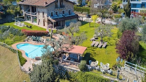 Une grande maison en pierre dotée d’une piscine, d’un patio couvert et d’un jardin bien entretenu.