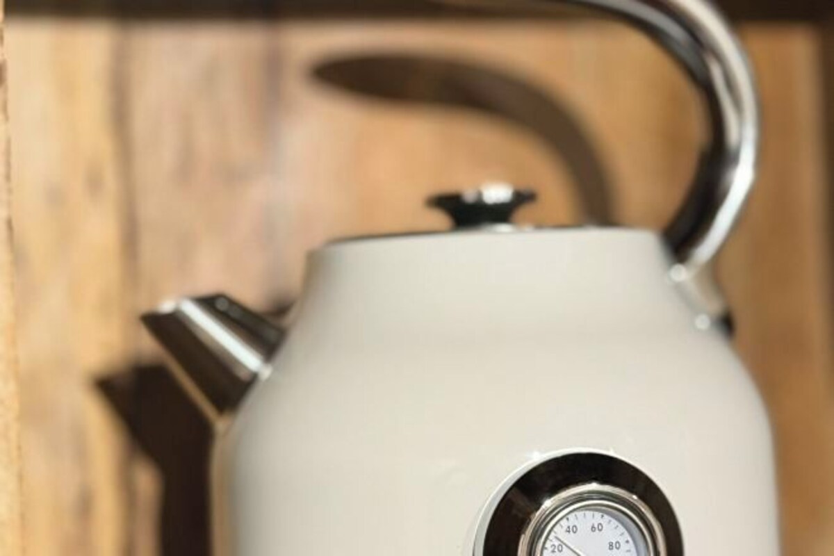 A white kettle with a metallic handle and a spout, featuring a pressure gauge.