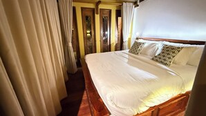 A hotel room with a large bed, wooden headboard, and curtains. - Kawarin Kanpuri Villas (Kanchanaburi)