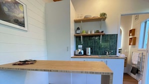 Una cocina moderna con una isla de madera, dos taburetes, una cafetera y un salpicadero de azulejos verdes.