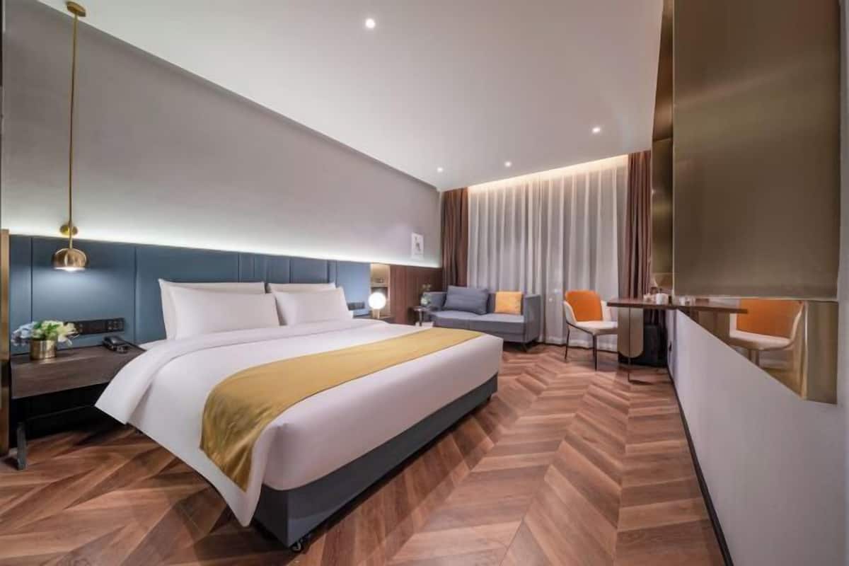 Quarto de hotel moderno com uma cama grande, uma escrivaninha, uma cadeira e uma mesinha.