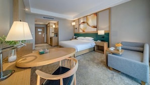 A hotel room with a bed, a desk, a chair, a sofa, and a wall with a decorative piece. - Jiyue Crystal Hotel (Nanning Convention and Exhibition Center Qingxiushan Subway Station) (Nanning)