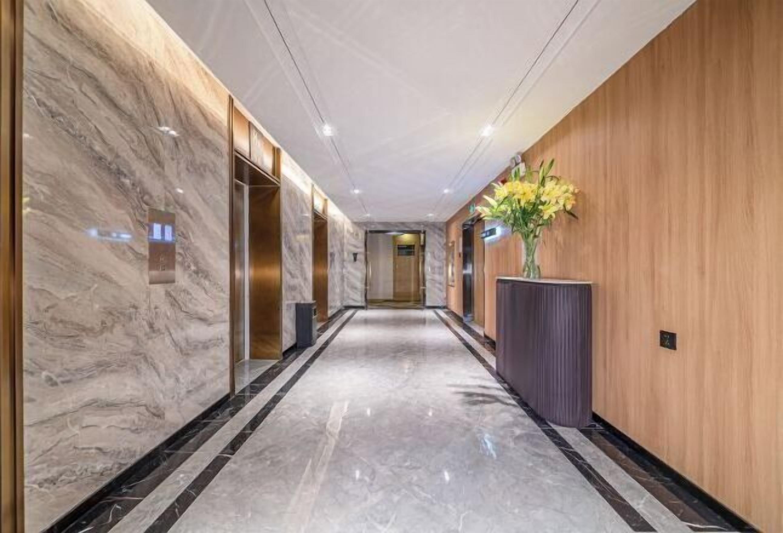 A modern hallway with marble walls, a wooden panel wall, and a marble floor.