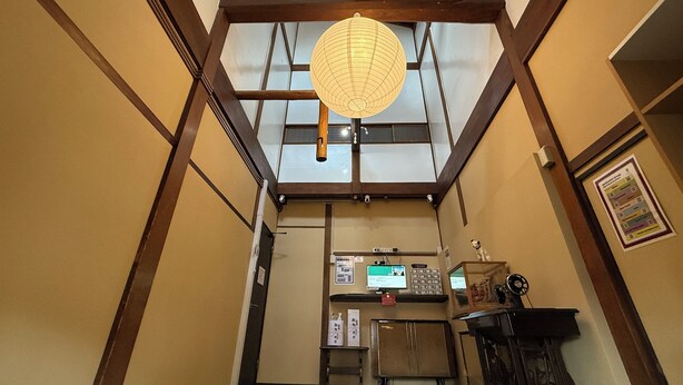 A traditional Japanese interior with a tatami mat floor, a shoji screen door, and a hanging paper lantern. - Backpackers Jinya (Takayama)