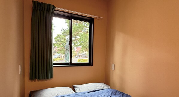 Une pièce avec un lit, une fenêtre donnant sur l’extérieur et un rideau.