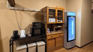 A kitchenette with a microwave, toaster, and refrigerator. There are cabinets with a sign instructing to wash dishes. - Backpackers Jinya (Takayama)