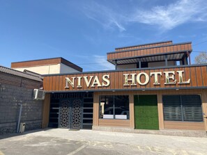 A hotel with a modern facade, large glass windows, and a prominent sign reading 'NIVAS HOTEL'. - Safo Hotel (Tashkent)