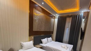 A hotel room with two beds, a desk, a chair, a large mirror, and a ceiling light fixture. - Safo Hotel (Tashkent)