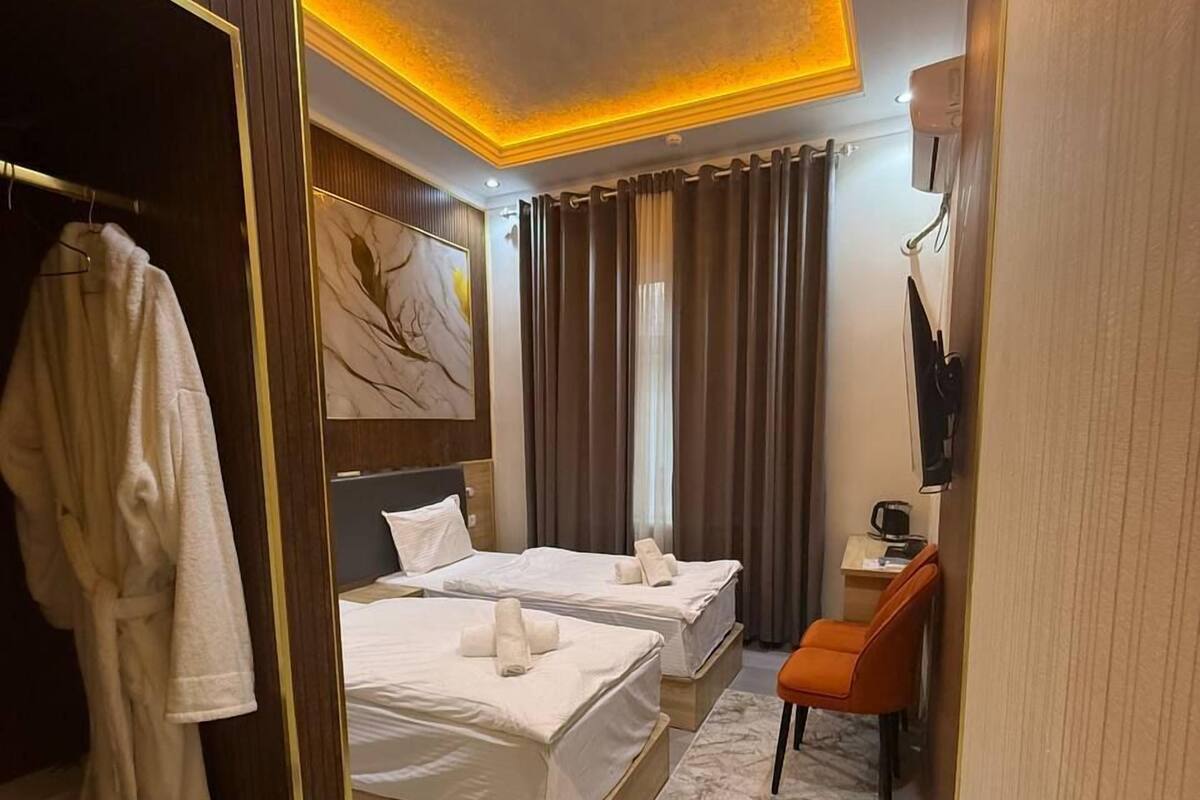 A hotel room with two beds, a robe rack, a desk with a chair, and a TV.