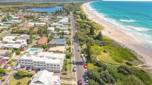 Une vue aérienne d’une ville côtière, avec une plage, des immeubles résidentiels et une route qui longe la plage.