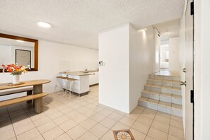 Eine moderne Küche mit Bar, einem Esstisch mit Hocker und einer Treppe zu einer weiteren Ebene.