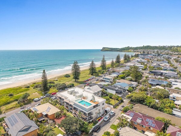 A coastal residential area with houses, a beach, and a clear view of the ocean.